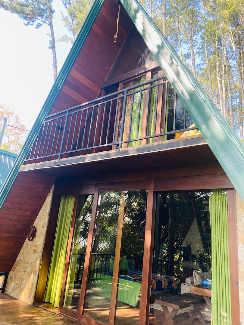 Daylight view of the steep A-frame cabana with timber walls, glass doors, and green curtains