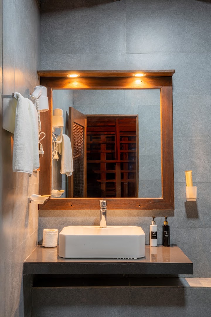 Gray tiled bathroom vanity with a timber framed mirror and warm lights